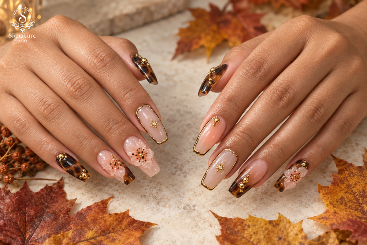 Long square fall nails with tortoiseshell tips, gold accents, and floral details